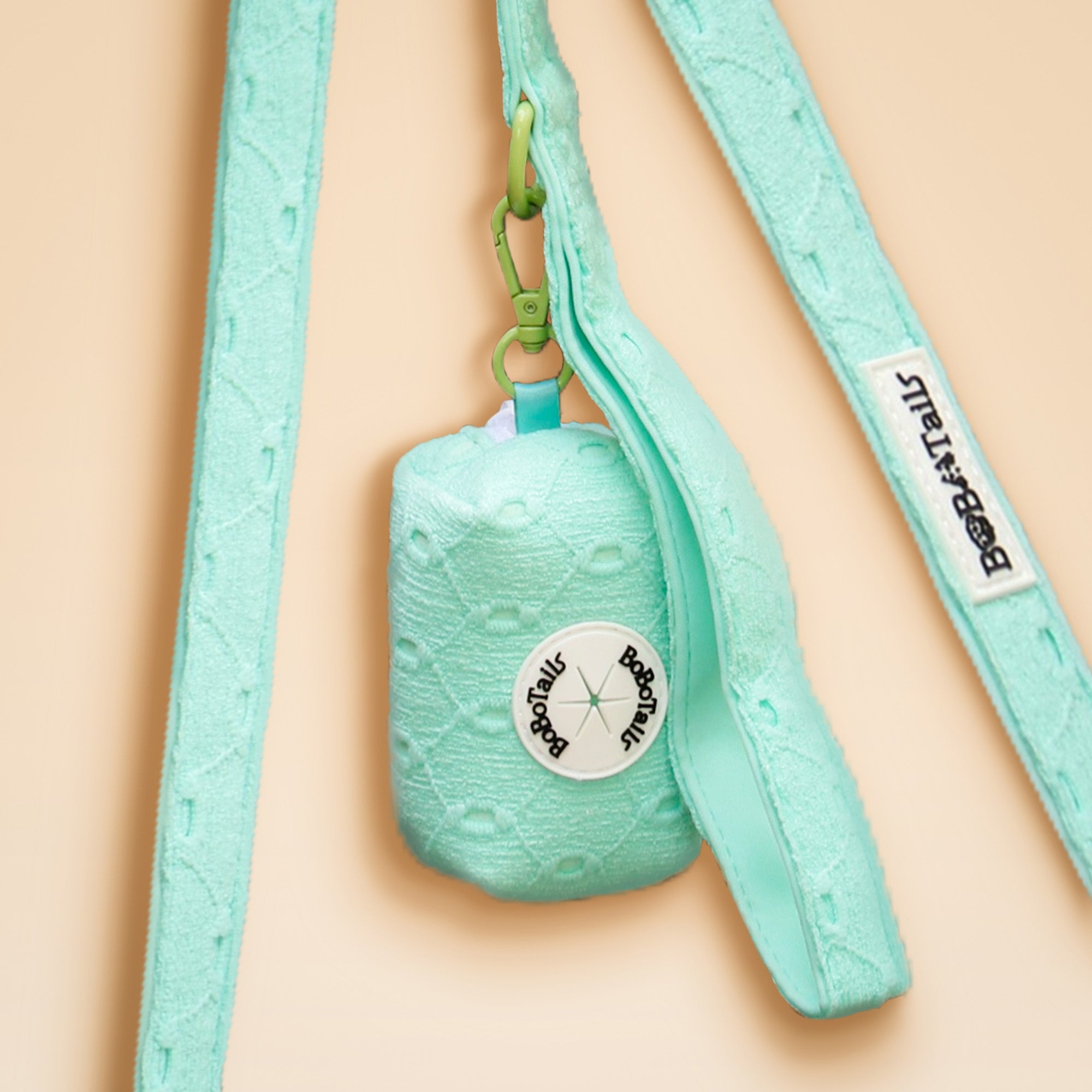 Mint green pet toy with a strap on a beige background