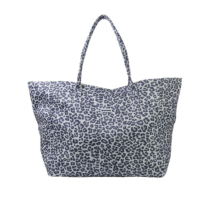 A canvas tote bag with a navy blue leopard print pattern on a white background, featuring two shoulder straps.