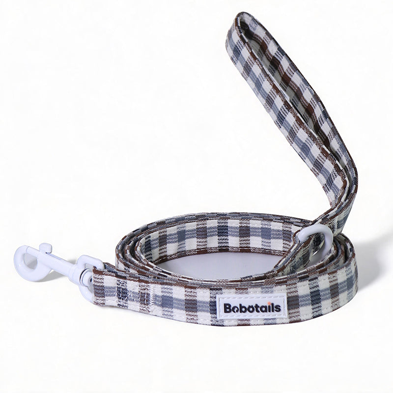 A plaid dog leash with a white clip and white D-rings, featuring a white label with the brand name 'Bobotails'. The leash has a  pattern of brown, gray, and white plaid, shown on a clean white background.