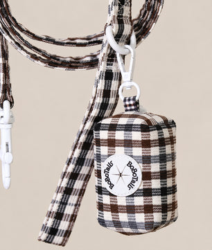 A brown, black, and beige plaid dog leash and matching bag set with white hardware, featuring a circular 'Bobotails logo patch on the bag, set against a solid beige background.