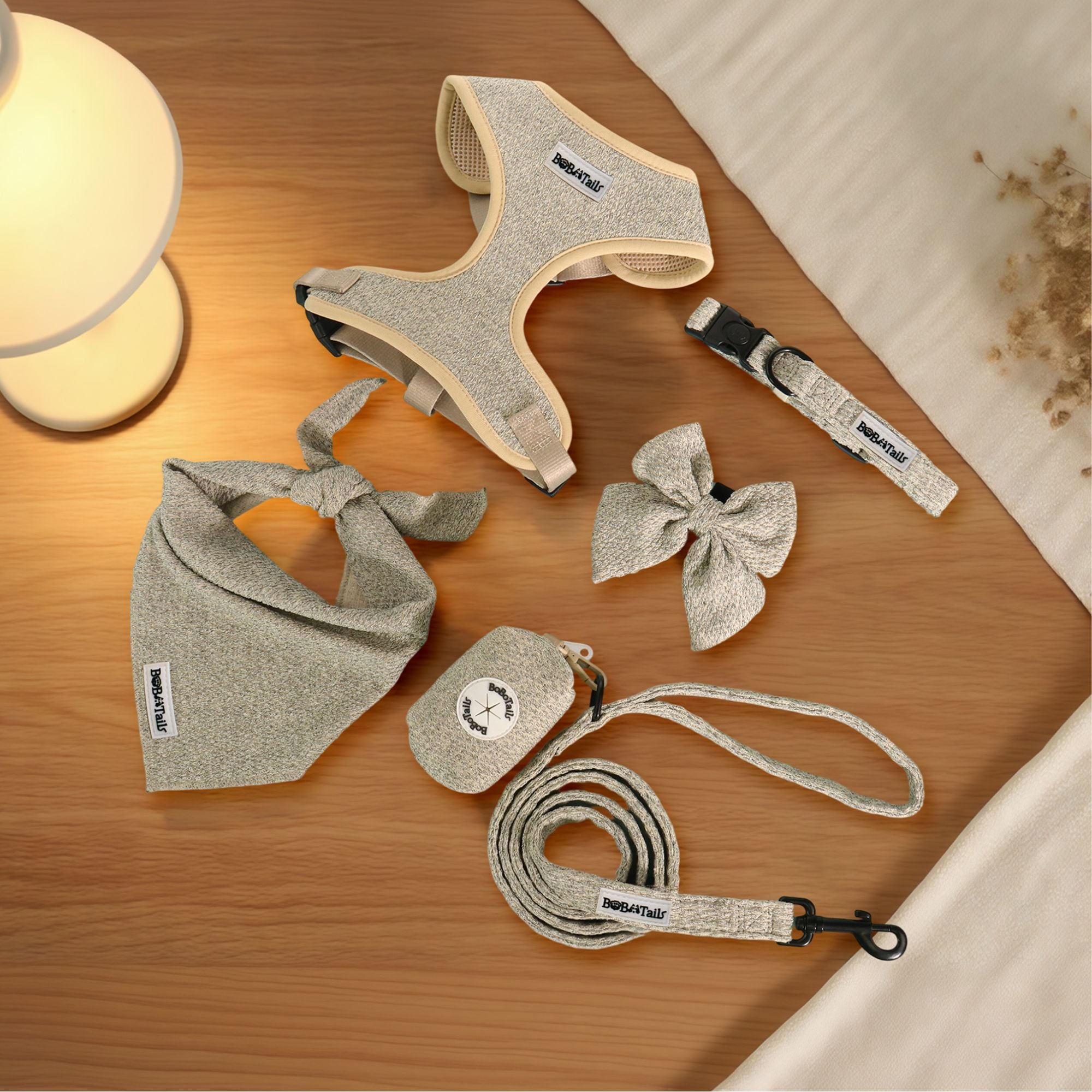 Dog accessories including a harness, leash, and bow on a wooden surface.